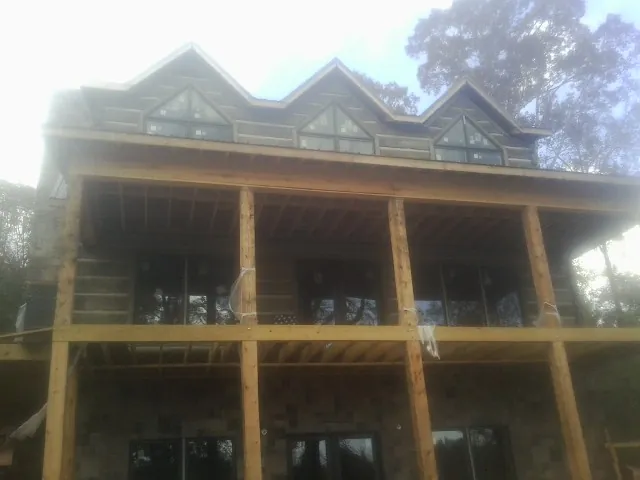 Dormers and porch framing on a large log home under construction — Roof Coating work by our crew in Dodge Center