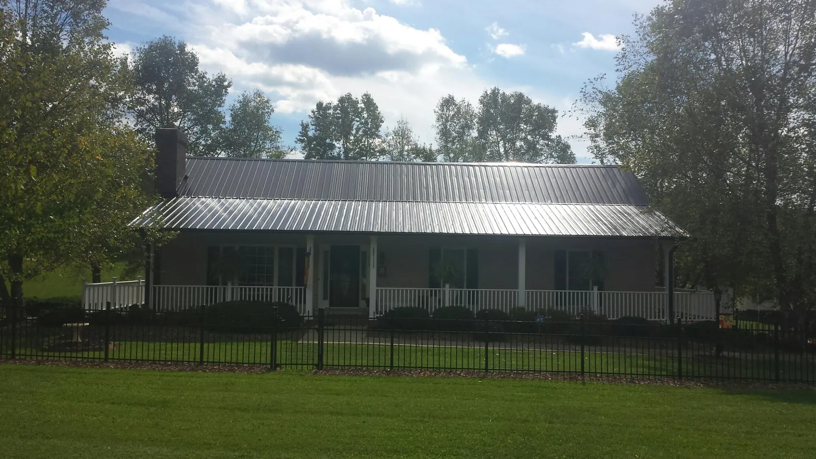 Gray metal roof on a brick ranch with a full width front porch — Gutter Guard Installation work by our crew in Dodge Center