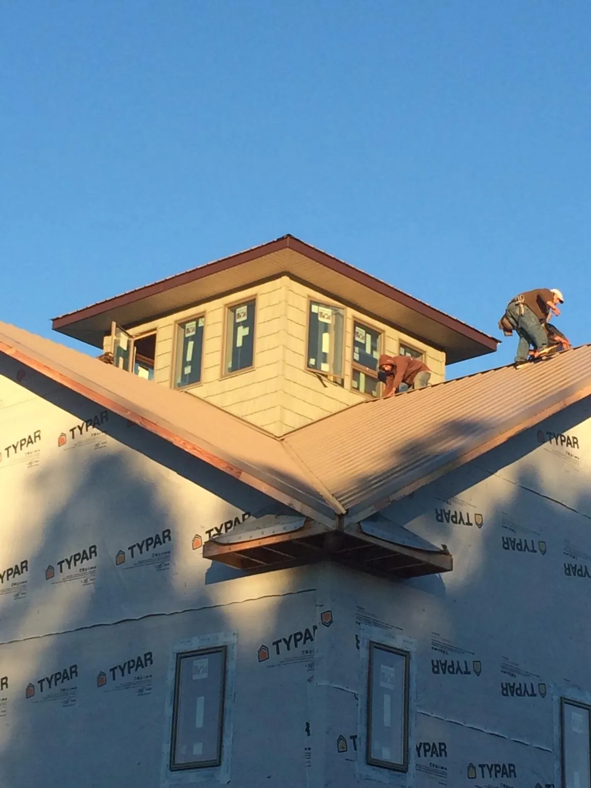 Roofers working around a rooftop cupola on a new metal roof at sunset — Roof Waterproofing in Dodge Center by Roofing Brothers